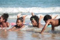 Group African kids in swimsuit have fun together on beach, boys and girls with black curly hair lying down in line at tropical sea Royalty Free Stock Photo