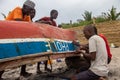 Group of African people fixing and maintaining fisherman\'s colorful wooden boat, at the shore of Indian Ocean