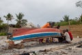 Group of African people fixing and maintaining fisherman\'s colorful wooden boat, at the shore of Indian Ocean