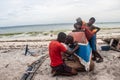 Group of African people fixing and maintaining fisherman\'s colorful wooden boat, at the shore of Indian Ocean