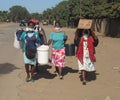 Group of African women with face masks carrying buckets