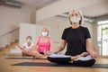 Group of aged ladies in masks sitting in lotus pose