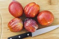 Five Amigo Pluots on a Wood Chopping Board with a Knife