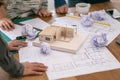 An architect feel stressed after working on architecture model together with shop drawing paper on table in office Royalty Free Stock Photo