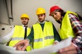 Group of architect watching some details on blueprints at construction site Royalty Free Stock Photo