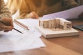 An architect working and discussing about an architecture model together with shop drawing paper on table in office Royalty Free Stock Photo