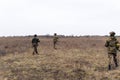 Group of armed Ukrainian soldiers walks through steppe