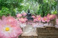 A group of artificial pink lotus flowers with black Buddha statues