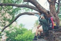 Group Asia women hiker with backpack on big tree checks map to find directions and look binoculars in wilderness area fores Royalty Free Stock Photo