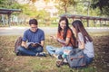 Group of Asian college student reading books and tutoring special class for exam on grass field at outdoors. Happiness and Royalty Free Stock Photo