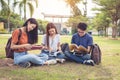 Group of Asian college student reading books and tutoring special class for exam on grass field at outdoors. Happiness and Royalty Free Stock Photo