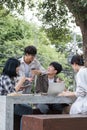 Group of Asian college student reading books and tutoring special class for exam on grass field at outdoors. Happiness Royalty Free Stock Photo