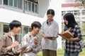 Group of Asian college student reading books and tutoring special class for exam on grass field at outdoors. Happiness Royalty Free Stock Photo