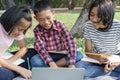 Group of Asian elementary school children working together and information search learning with laptop in the summer at the park Royalty Free Stock Photo