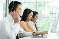 Group of Asian employee work in telemarketing customer service teams. Young operator man working with headset smiling Royalty Free Stock Photo