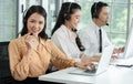 Group of Asian employee work in telemarketing customer service teams. Young operator woman working with headset smiling Royalty Free Stock Photo