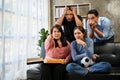 Group of Asian friends football fans watching football or soccer match on TV at home together