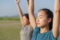 Group of Asian people practicing yoga In the prayer position and raised hands while standing outdoor in the summer,  Asia girl Royalty Free Stock Photo