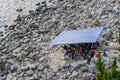 Group of Asian People Resting and Talking on Stony Beach under Tent