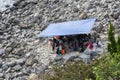 Group of Asian People Resting and Talking on Stony Beach under Tent