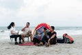 a group of asian people sitting and hangout on top of a sandy beach, socializing and outdoor activities of teenagers concept