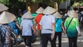 Group of Asian tourists in Vietnamese conical hats walk in the street in Hoi An