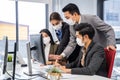 Group of Asian young business people working on computer in office with new normal lifestyle. Man and woman wear protective face m Royalty Free Stock Photo