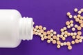 Capsules spilling out of white bottle. Purple background. Line, Royalty Free Stock Photo