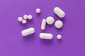 Group of assorted white tablets. Violet background. Royalty Free Stock Photo