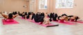 A group athletic women doing pilates or yoga on pink mats in front of a window in a beige loft studio interior. Teamwork