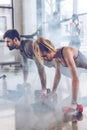 Group of athletic young people in sportswear doing push ups with dumbbells at the gym Royalty Free Stock Photo