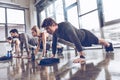 Group of athletic young people in sportswear doing push ups or plank at the gym