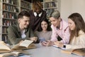 Group of attractive teenage multi ethnic schoolmates using modern smartphone