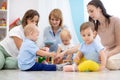 Group of babies and mothers playing with colorful educational toys in nursery room Royalty Free Stock Photo