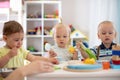 Group of babies is playing at table in nursery or creche. Toddlers in the day care center. Fun in the children`s