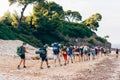 Group of backpackers walking on a sandy road along the sea shore