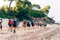 Group of backpackers walking on a sandy road along the sea shore