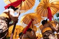 Group of Balinese dancer in ethnic costumes with traditional colorful umbrellas on hindu ceremony parade during temple festival.