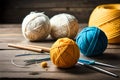 A group of balls of yarn and knitting needles on a table with yarn balls and needles in the middle of the image and a ball of yarn