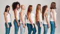 Group of beautiful diverse young women wearing white shirt and denim jeans looking aside while posing, standing isolated Royalty Free Stock Photo