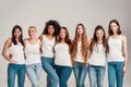 Group of beautiful diverse young women wearing white shirt and denim jeans looking at camera while posing together Royalty Free Stock Photo