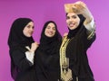 group of beautiful muslim women two of them in fashionable dress with hijab using mobile phone while taking selfie Royalty Free Stock Photo