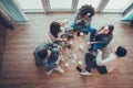 Group of beautiful young people sitting on floor in office having fun together playing name game with sticky notes to their Royalty Free Stock Photo
