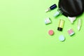 Group of beauty cream bottles dropped out of the cosmetics bag on green background. Space for your design. Top view of skincare