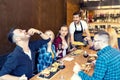 Group of best friends eating tasty food in small restaurant while happy owner serving them Royalty Free Stock Photo