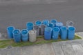A group of blue and grey garbage cans over a sidewalk grass Royalty Free Stock Photo