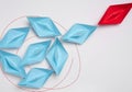 Group of blue paper boats heading in one direction and one red one heading in the opposite direction