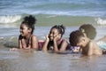 Group of boys and girls lie down in shallow sea water, cute kids having fun on sandy summer beach, happy childhood friend playing Royalty Free Stock Photo