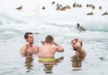 Group of boys or men ice bathing in the freezing cold water of a frozen lake