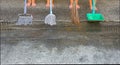 A group of boys standing on bare feet holding broom, mop, scoop